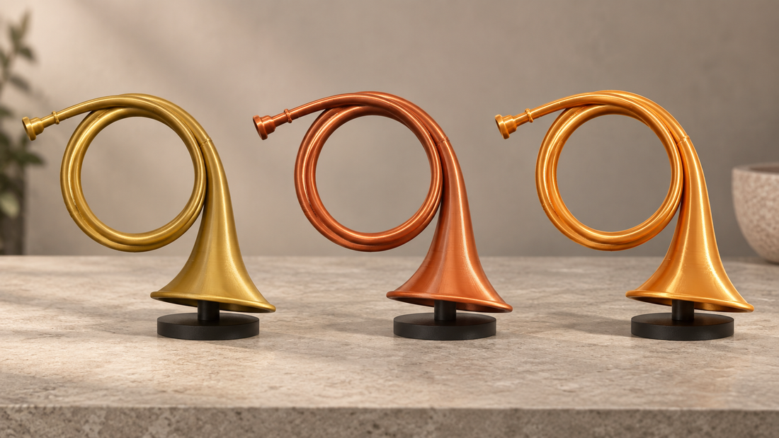 Drie identieke 3D-geprinte jachthoorns in goudkleurig, koperkleurig en glanzend silk filament